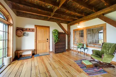 a living room with wooden floors and a wooden door at Breathtaking Mtn Views Stylish Rustic Retreat! in Bennington