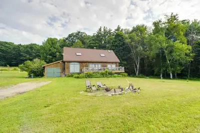 a house with a group of chairs in a field at Breathtaking Mtn Views Stylish Rustic Retreat! in Bennington