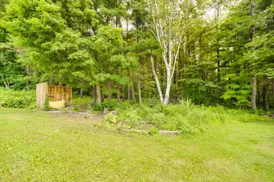 a garden with a fence and trees and grass at Breathtaking Mtn Views Stylish Rustic Retreat! in Bennington