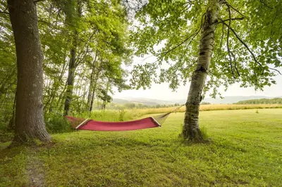 a red hammock hanging between two trees in a field at Breathtaking Mtn Views Stylish Rustic Retreat! in Bennington