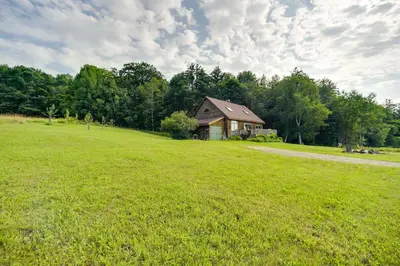 a house in the middle of a green field at Breathtaking Mtn Views Stylish Rustic Retreat! in Bennington