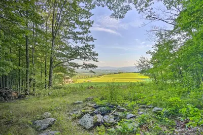 a field of yellow rapeseed in the distance with trees at Breathtaking Mtn Views Stylish Rustic Retreat! in Bennington