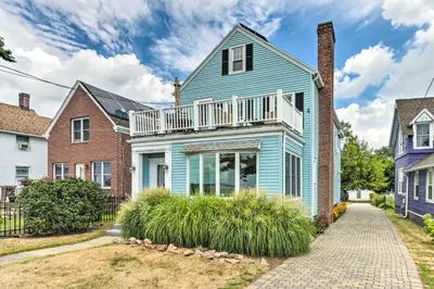 a blue house with a balcony on a street at Walkable New Haven Retreat with Ocean Views! in New Haven