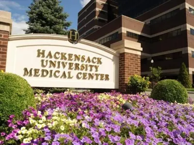 a sign for the haccost university medical center with purple flowers at Elegant Main Street Living* Near NYC in Hackensack