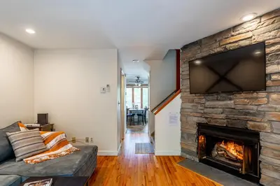 a living room with a stone fireplace with a flat screen tv at Redwood Retreat in Windham - minutes to Mtn! in Windham
