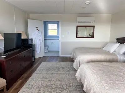 a bedroom with two beds and a tv and a mirror at Blue Vista Motor Lodge in Florida