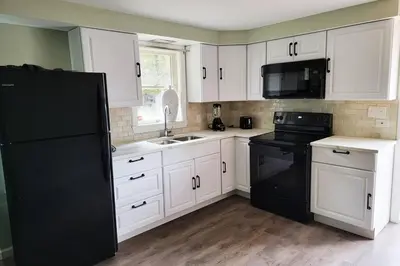a kitchen with white cabinets and a black refrigerator at Lake Access! Catskill Cozy Home- Hot-Tub, Sauna in Loch Sheldrake