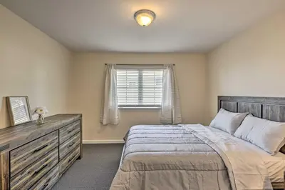 a bedroom with a bed with a dresser and a window at Glen Cove Home Walk to Boardwalk and Dining! in Glen Cove
