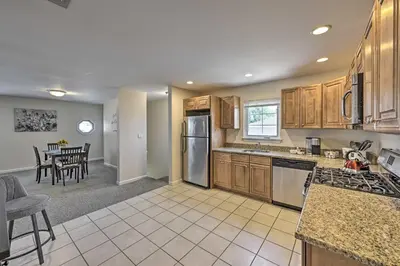 a kitchen with wooden cabinets and a dining room at Glen Cove Home Walk to Boardwalk and Dining! in Glen Cove