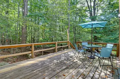 a wooden deck with a table and an umbrella at Poconos Cabin Serene Deck, Fire Pit and Game Room in Tobyhanna