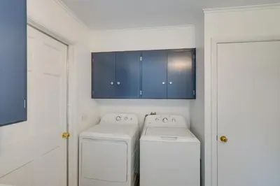 a laundry room with a washer and dryer and blue cabinets at Water-View Home in the Berkshires in Sheffield