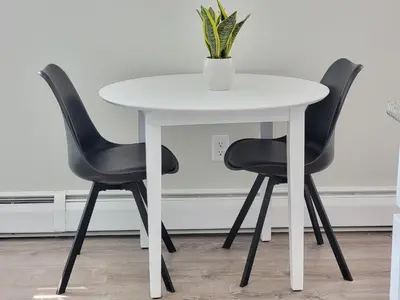 a white table with two black chairs and a vase on it at 1 Bedroom apartment in Hartford