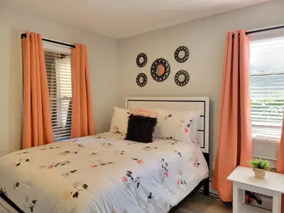 a bedroom with a bed and two windows with orange curtains at 1 Bedroom apartment in Hartford