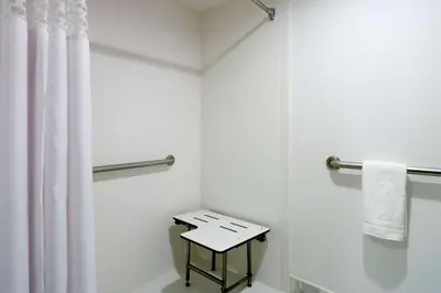 a white bathroom with a shower curtain and a table at Hilton Garden Inn New York Manhattan Midtown East in New York