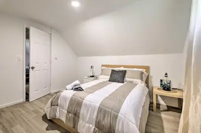 a white bedroom with a large bed and a table at Chic Tobyhanna Home with Furnished Deck Space! in Tobyhanna