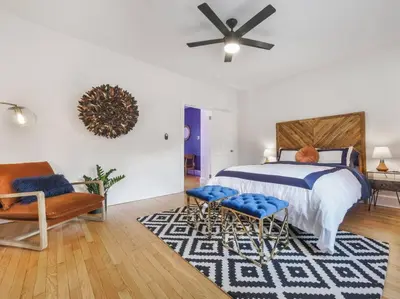 a bedroom with a bed and two chairs and a ceiling fan at MidCentury Mod Suite, Hudson River/Mt Beacon Views in Newburgh
