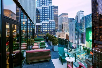 a balcony with chairs and tables and a city skyline at citizenM New York Times Square in New York
