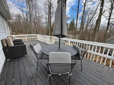 a table and chairs on a deck with an umbrella at Casa Rosado @ Pocono II by Lake Hot Tub Camelback in Tobyhanna