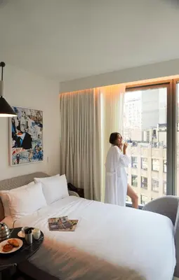 a woman in a hotel room looking out the window at Virgin Hotels New York City in New York