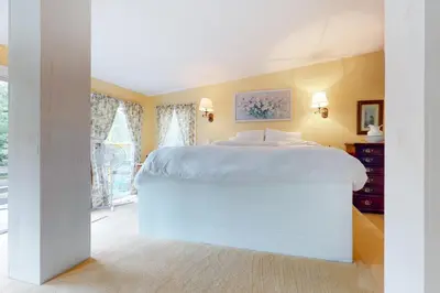 a large white bed in a bedroom with yellow walls at Hoot Owl Hollow in Jacksonville