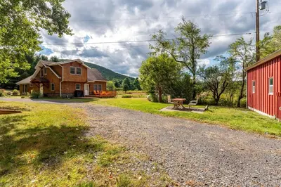 a house and a red barn and a gravel road at Beautiful mountain home with gorgeous meadow views in Hunter