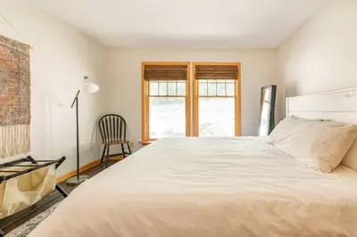 a bedroom with a large white bed and a chair at Beautiful mountain home with gorgeous meadow views in Hunter
