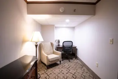 a room with a chair and a desk and a lamp at Best Western Plus Fairfield Executive Inn in Fairfield