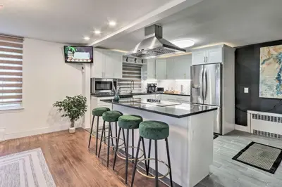 a kitchen with a island with bar stools at Upscale Waterbury Retreat with Indoor Hot Tub! in Waterbury