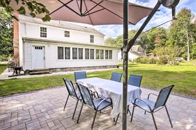 a table and chairs under an umbrella on a patio at Upscale Waterbury Retreat with Indoor Hot Tub! in Waterbury
