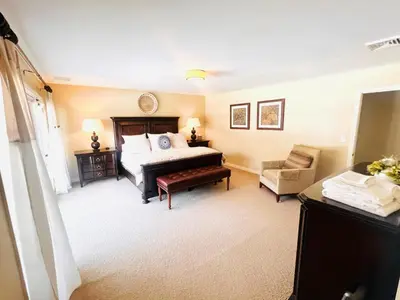 a bedroom with a bed and a chair at The Manor-Stunning Modern Farmhouse with Hot Tub in Dover