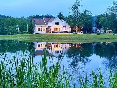 a house reflected in a pond at dusk at The Villa - Industrial Farmhouse with Hot Tub in Dover