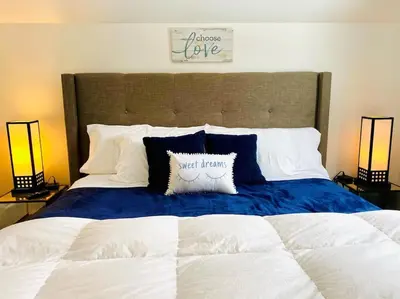a large bed with a blue and white blanket and two lamps at The Villa - Industrial Farmhouse with Hot Tub in Dover