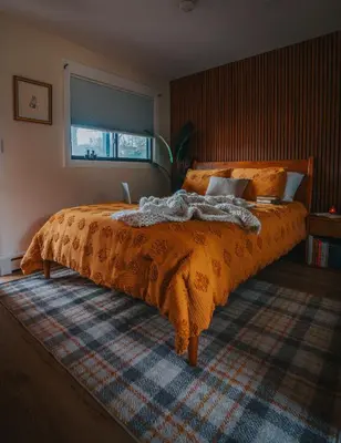 a bed with an orange comforter in a bedroom at The Willow, Catskill in Catskill