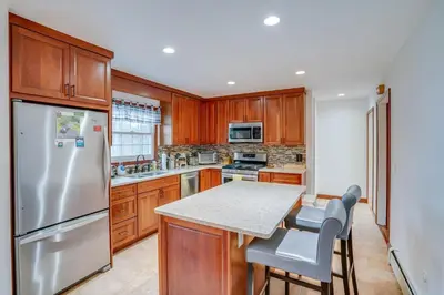 a kitchen with wooden cabinets and a stainless steel refrigerator at Woodstock Getaway with Hot Tub about 2 Mi to Dtwn! in Woodstock