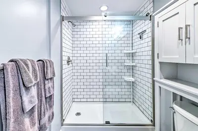 a bathroom with a shower with white tiles at Cozy and Walkable Delmar Getaway with Fire Pit! in Delmar