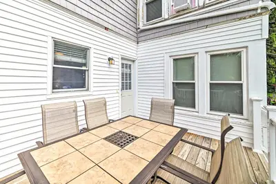 a patio with three chairs and a wooden table at Cozy and Walkable Delmar Getaway with Fire Pit! in Delmar