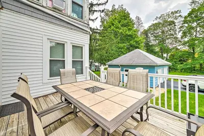 a wooden deck with a table and chairs on a house at Cozy and Walkable Delmar Getaway with Fire Pit! in Delmar