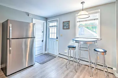 a kitchen with a stainless steel refrigerator and bar stools at Cozy and Walkable Delmar Getaway with Fire Pit! in Delmar