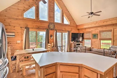 a log cabin kitchen and living room with a ceiling fan at Grand Windham Retreat with Fire Pit and Game Room in Windham