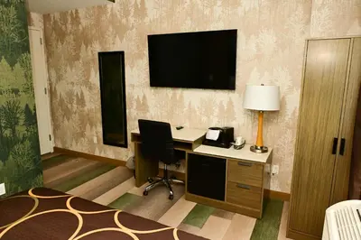 a hotel room with a desk and a television on the wall at Super 8 by Wyndham Bronx Near Botanical Garden in Bronx