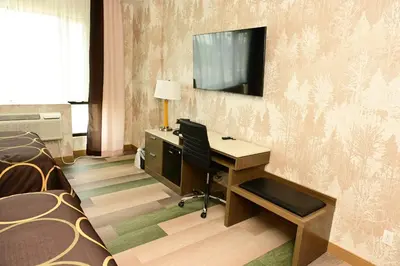 a room with a desk and a television on a wall at Super 8 by Wyndham Bronx Near Botanical Garden in Bronx