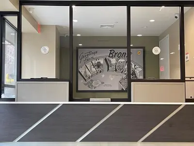 a lobby with a door with a sign that says bronx at Super 8 by Wyndham Bronx Near Botanical Garden in Bronx