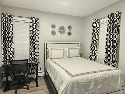 a bedroom with a bed and a chair and windows at 1 Bedroom Apartment in Hartford