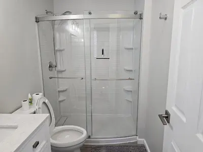 a white bathroom with a shower and a toilet at 1 Bedroom Apartment in Hartford