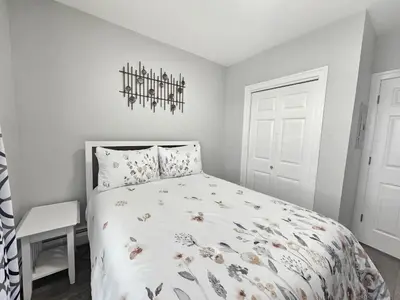 a white bedroom with a bed and a chandelier at 1 Bedroom Apartment in Hartford