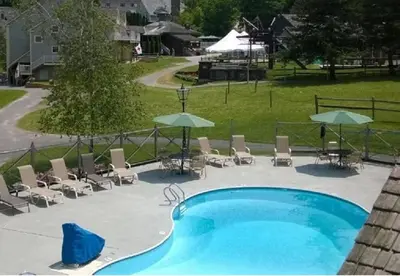 a swimming pool with chairs and umbrellas at Ski On Off 1BR Suite 1st Flr Sleeps 4 Jiminy Peak in Hancock