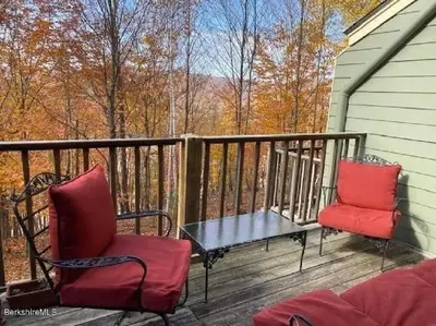 a patio with two chairs and a table on a deck at Spacious 3BR 3BA Sleeps 8 Ski On Off Jiminy Mountain Resort in Hancock