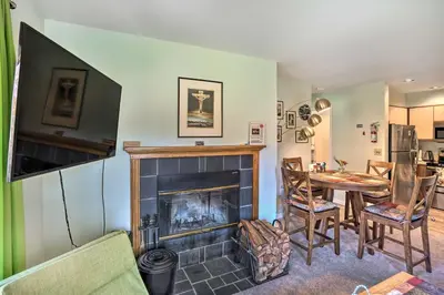 a living room with a fireplace and a table at Comfortable Dover Apartment Walk to Mt Snow! in Dover