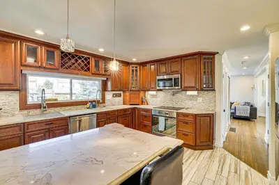a large kitchen with wooden cabinets and a counter top at Near Yale and Lighthouse Point Beach Home with Pool! in New Haven