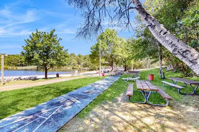 a park with benches and a tree and water at Tree and Easy in Tobyhanna